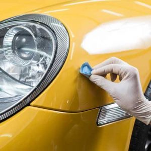 person polishing fresh bright yellow paint on sports car