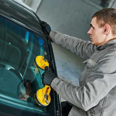 man replacing windshield with suction cup tool